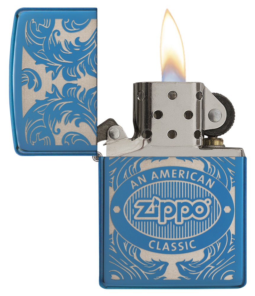 Open voorkant blauwe Zippo aansteker met vlam omgeven door een lasergegraveerd filigraan motief met het Zippo-logo en "an american classic".